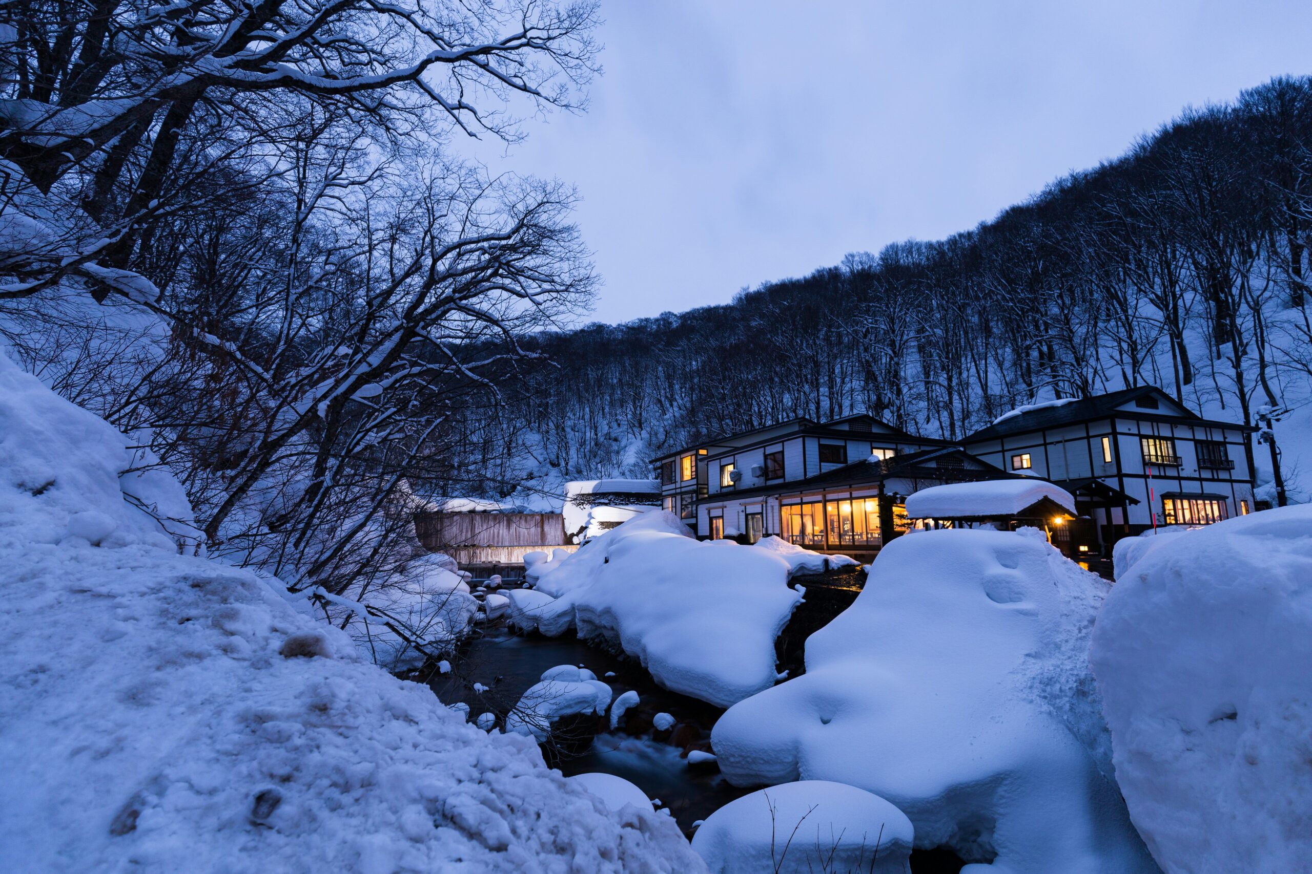 Taenoyu Onsen, célèbre station thermale de Nyuto-Onsenkyo à Akita, Japon, illuminée après le coucher du soleil et entourée de neige.